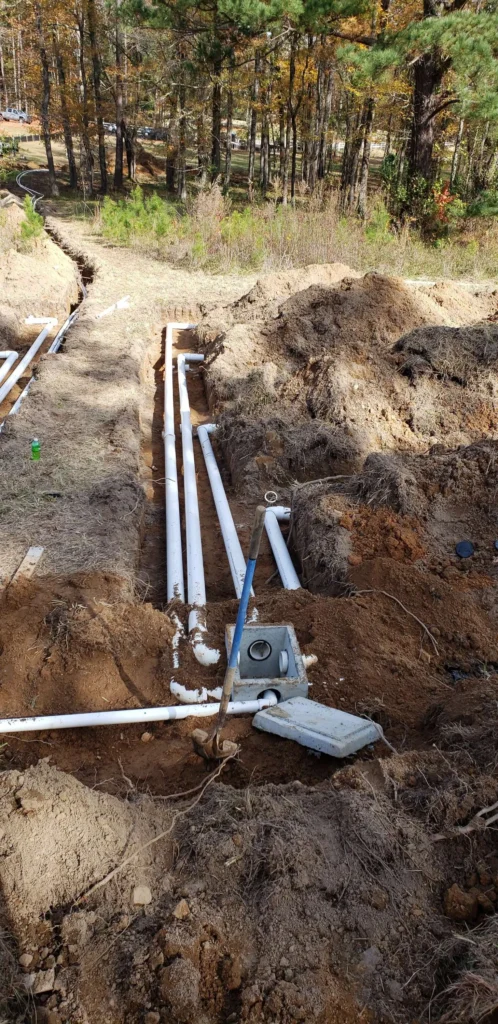Sewer line and fittings exposed in an open excavation, Carolina Septic, CSRA