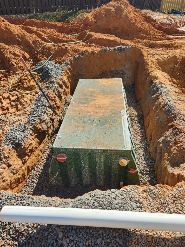 Large tank set into a gravel-lined excavation, Carolina Septic, CSRA