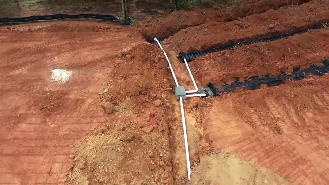 Chamber drainfield installation in red Piedmont clay, distribution box feeding three laterals, CSRA